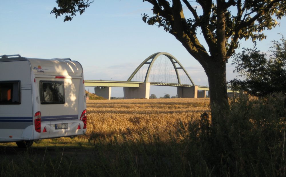 Ein Wohnwagen steht vor der Kulisse der Fehmarnsundbrücke